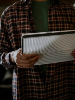 A mechanic holding a car air filter, focusing on automotive maintenance indoors.