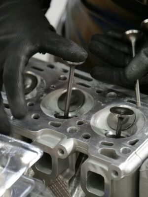 Close-up of mechanic's hands working on engine cylinder head assembly with valves.