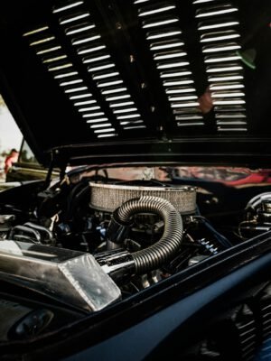 Detailed view of vintage car engine with open hood on a sunny day.
